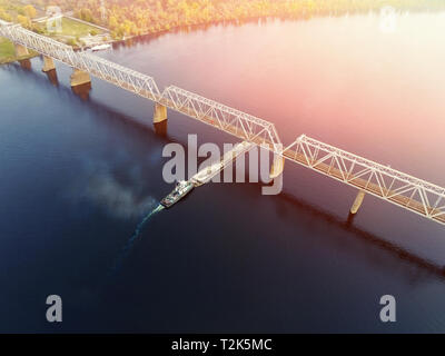 Scenic aerial cityscape di Kiev e il fiume Dnipro al tramonto. Rimorchiatore chiatta di supporto con sabbia di materiali alla rinfusa voce lungo il fiume Dnieper. In Ucraina Foto Stock