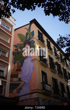 Grande murale di una donna dipinta sul lato di un edificio residenziale, incorniciata da foglie, Madrid, Spagna Foto Stock