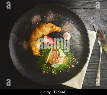 La ciliegia e lo strudel di mele servito con una pallina di gelato alla vaniglia su ceramica la piastra nera. vista dall'alto. Foto Stock