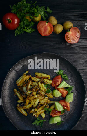 Cucinati freschi Patate fritte con cipolle e funghi close-up su una piastra in legno nero e tavola orizzontale. Foto Stock