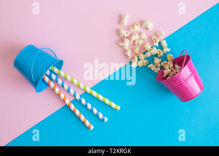 Piatto di laici piccole benne di metallo con popcorn e bere cannucce su sfondo pastello minimo concetto creativo. Foto Stock