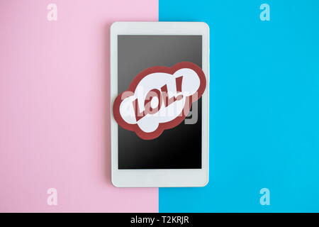 Piatto di laici digitale compressa dispositivo o telefono cellulare con lol testo in discorso bolla contro lo sfondo color pastello tecnologia minima concetto creativo. Foto Stock
