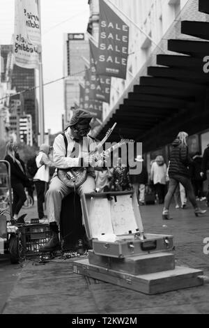 Suonatore ambulante di strada suonando la chitarra con una maschera a gas su Foto Stock