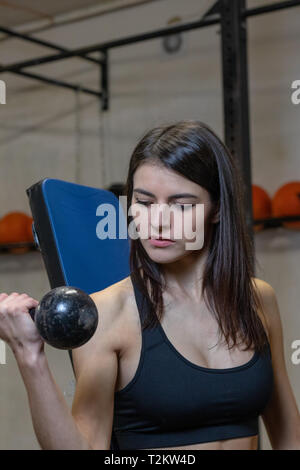 La ragazza è impegnata con manubri in palestra Foto Stock