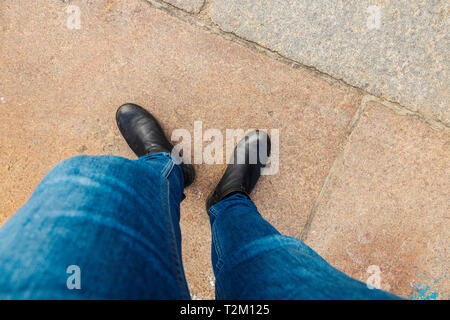 Al di sopra di vista di due gambe in jeans e stivali. Foto Stock