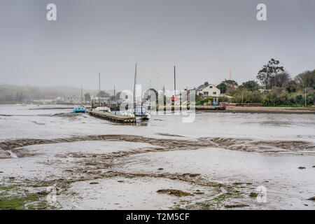 Un paesaggio di Millbrook Lago off Tamar estuario, East Cornwall. La marea è fuori e le barche sono in appoggio sul fondo fangoso attraccata alla banchina Foto Stock