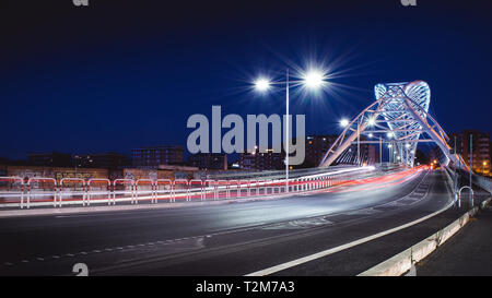 Roma, Italia - 7/31/2019: il moderno ponte bianco dedicato a Settimia Spizzichino, di notte, con i sentieri della luce dei fari di automobile e la str Foto Stock