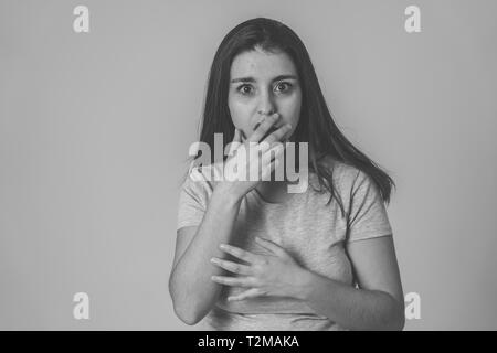 Bianco e nero ritratto di giovane donna sensazione spaventato e scioccato rendendo la paura, ansia gesti. Guardando terrorizzata e coprendo la sua bocca. Spazio di copia Foto Stock