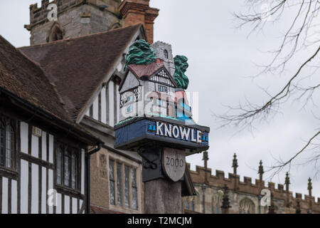 Segno colorato nel villaggio di Knowle, vicino a Solihull con il modello di edificio in cima Foto Stock