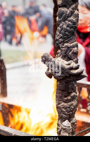 Close up di un altare con dragon carving, incenso bruciatore, joss pot, bastoncini di incenso bruciare con i fumi in un tempio buddista Foto Stock