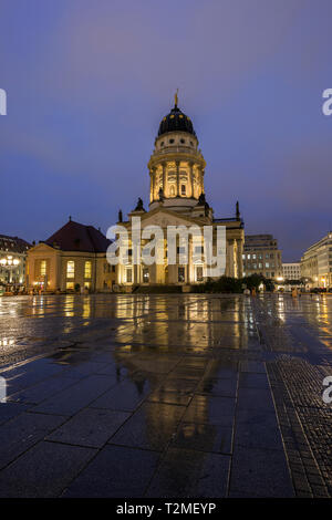 Illuminata Französischer Dom (cattedrale francese) e la sua riflessione in corrispondenza della wet piazza Gendarmenmarkt a Berlino, Germania, la sera. Foto Stock