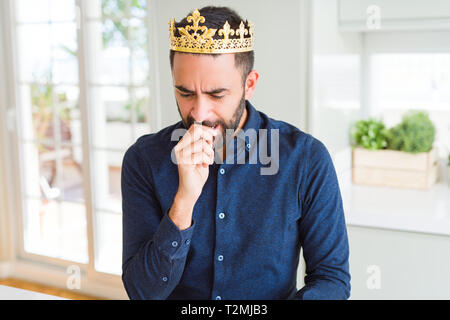 Bel uomo ispanico indossando Golden crown sopra la testa come il re cercando stressato e nervoso con le mani sulla bocca di mordere le unghie. Problema d'ansia. Foto Stock