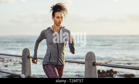 Giovane donna in esecuzione in serata. Femmina in sportswear jogging sul lungomare. Foto Stock