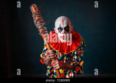 Mad sanguinosa clown con la mazza da baseball. L'uomo con il trucco in costume di halloween, zombie Foto Stock