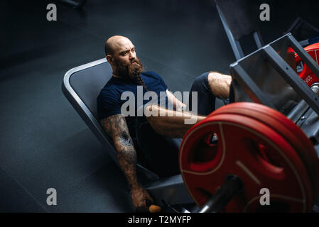 Forte atleta sulla macchina ginnica con barbell, formazione in palestra. Uomo Barbuto in allenamento in sport club, uno stile di vita sano Foto Stock