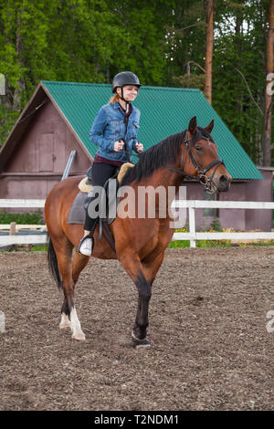 Corsi di equitazione per principianti, ragazza adolescente e marrone a cavallo il maneggio, foto verticale Foto Stock