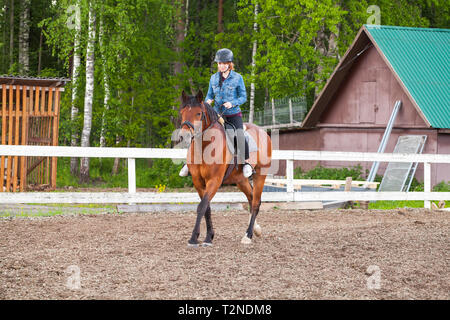 Lezioni di equitazione, adolescente ragazza caucasica passeggiate a cavallo il maneggio all'aperto Foto Stock
