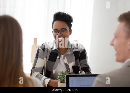 Felice nero donna del team leader con i colleghi lavoratori seduti insieme in office boardroom. Successo femminile americano passando il colloquio di lavoro, i consulenti Foto Stock