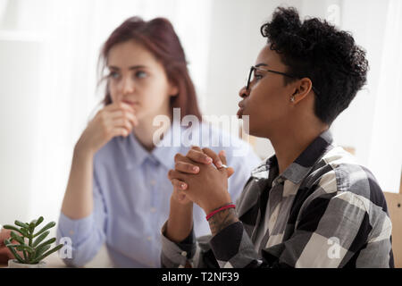 In prossimità della messa a fuoco sul nero africano leader del team boss seduta parlando a discutere con i colleghi in ufficio. Grave fiducioso femmina nero di prendere una decisione, Foto Stock