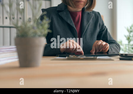 Imprenditrice utilizzando tablet in ufficio, moderno e contemporaneo gadget tecnologia nelle operazioni aziendali Foto Stock