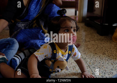 Indian Bengali infantile bellissima bambina sta giocando dentro la sua casa con un nipplo di plastica nella sua bocca. Foto Stock