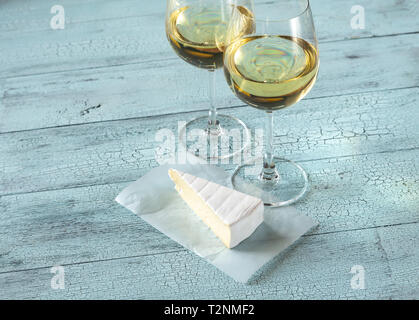 Due bicchieri di vino bianco con Brie sullo sfondo di legno Foto Stock