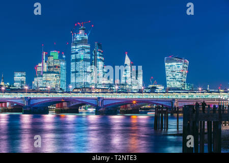 Skyline del quartiere finanziario di notte, il Tamigi sul primo piano, città di Londra, Regno Unito Foto Stock