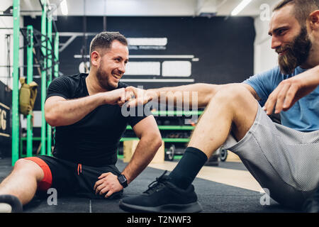 Personal trainer e uomo con disabilità godendo di conversazione in palestra Foto Stock