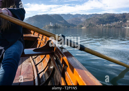 Giovane donna con paletta su una barca di legno - Lago di Bled Slovenia il canottaggio su barche di legno in una giornata di sole Foto Stock