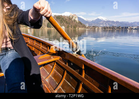 Giovane donna con paletta su una barca di legno - Lago di Bled Slovenia il canottaggio su barche di legno in una giornata di sole Foto Stock