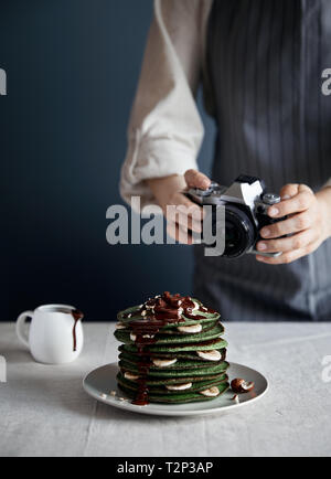 Mamma blogger fotografie verde Pancake fatti in casa con ripieno di spinaci, banana, avena e cioccolato su sfondo grigio Foto Stock