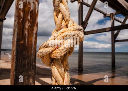 In prossimità di una spessa di colore arancio annodato la corda appesa da un molo su una spiaggia in Hartlepool nel nord est dell' Inghilterra Foto Stock