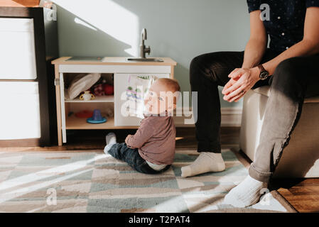 Bambino seduto sul soggiorno rug accanto al padre Foto Stock