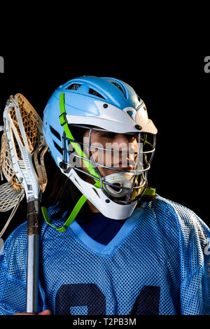 Giovane maschio lacrosse player con lacrosse stick, ritratto su sfondo nero Foto Stock