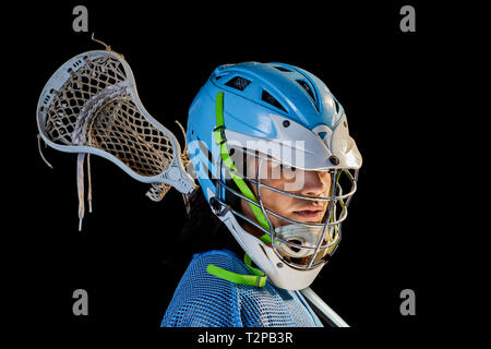 Giovane maschio lacrosse player con lacrosse stick, ritratto su sfondo nero Foto Stock