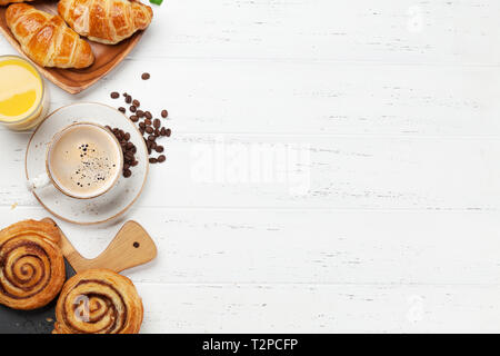 Caffè, cornetti, succo di arancia, panini alla cannella e le bacche di prima colazione. Su un tavolo di legno. Vista da sopra con copia spazio per il testo Foto Stock