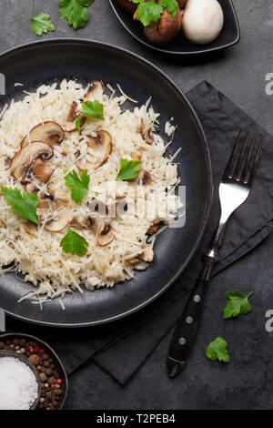 Delizioso risotto ai funghi conditi con formaggio parmigiano e prezzemolo. Vista superiore Foto Stock