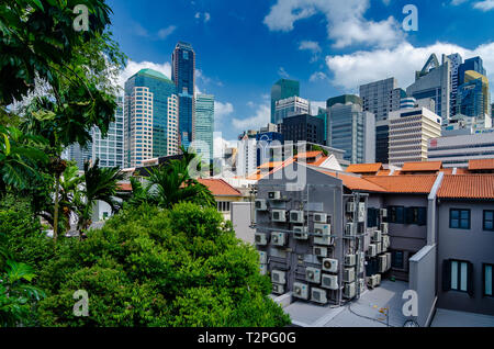 Un edificio residenziale con molti condizionatori d'aria è sopraffatte dal Singapore alto e moderno di blocchi Foto Stock