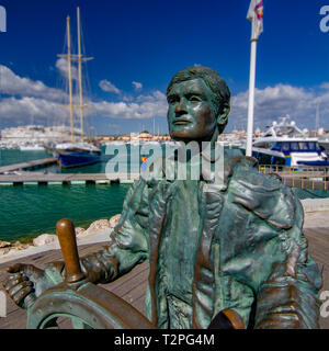 Una statua di bronzo di un timoniere si affaccia sul lungomare di Marina di Vilamoura, Portogallo Foto Stock