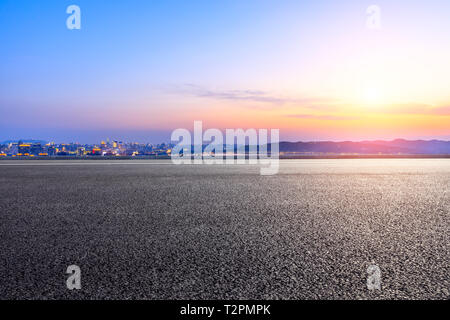 Svuotare strada asfaltata passando attraverso la città al di sopra di Hangzhou al tramonto Foto Stock
