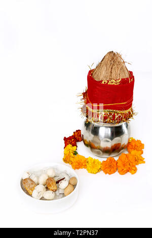 Kalash con noce di cocco e chunni con decorazioni floreali per navratri pooja. Foto di dryfruit nel recipiente. Isolato su uno sfondo bianco. Foto Stock