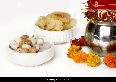 Kalash con noce di cocco e chunni con decorazioni floreali per navratri pooja. Immagine della frutta secca e potato chips nel recipiente. Isolato sul bianco bac Foto Stock