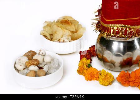 Kalash con noce di cocco e chunni con decorazioni floreali per navratri pooja. Ritratto di frutta secca e potato chips nel recipiente. Isolato sul bianco ba Foto Stock