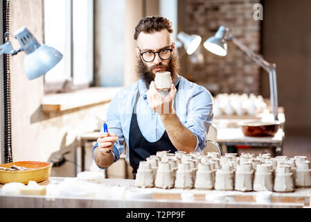 Uomo in blu t-shirt grembiule e lavorare nel vecchio studio atmosferica  spazzolatura vaso di pietra sul tavolo Foto stock - Alamy
