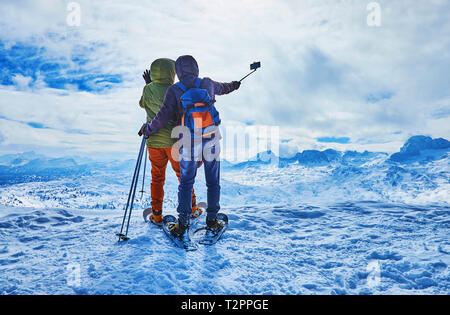 La coppia di snowshoers rende felice selfie, rimanendo sul bordo di montaggio Krippenstein alla fine della lunga salita e con una vista su misty mountai Foto Stock