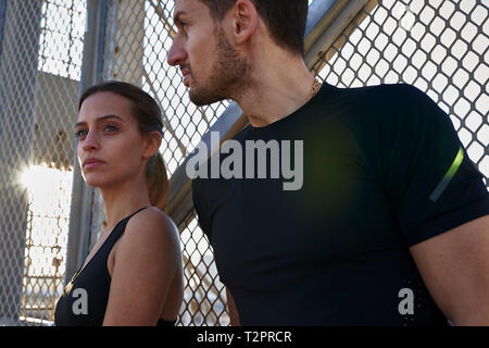 Amici facendo rompere accanto a parete recintata in stadio sportivo Foto Stock