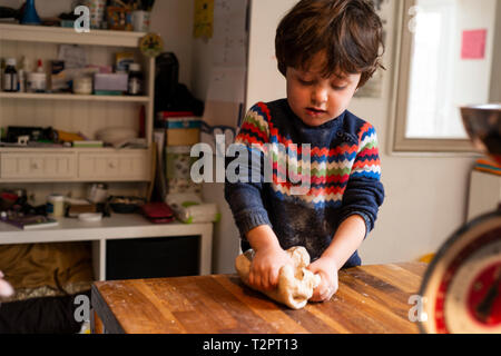 Il Toddler lavorazione dell'impasto sul piano di lavoro della cucina Foto Stock