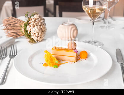 Delis di foie gras e di mango - Pralina di foie gras e polvere di poker, gel mango, sfera e spugna, servita in una piastra bianca. Foto Stock