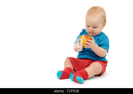 Ragazzino con un Apple seduto su sfondo bianco, isolato Foto Stock