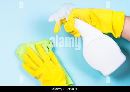 Donna di pulizia parete blu con il panno in microfibra e spray per la pulizia di agente. Foto Stock
